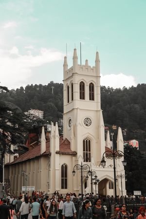Gothic architecture of Christ Church in Shimla with a bustling crowd and scenic hills in the background.